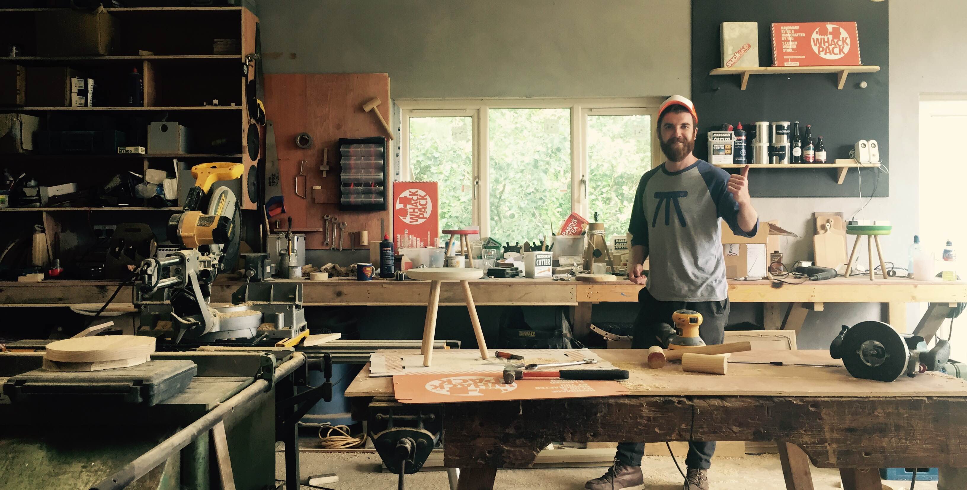 Man in workshop wearing a printed t-shirt with an abstract stool image on front.