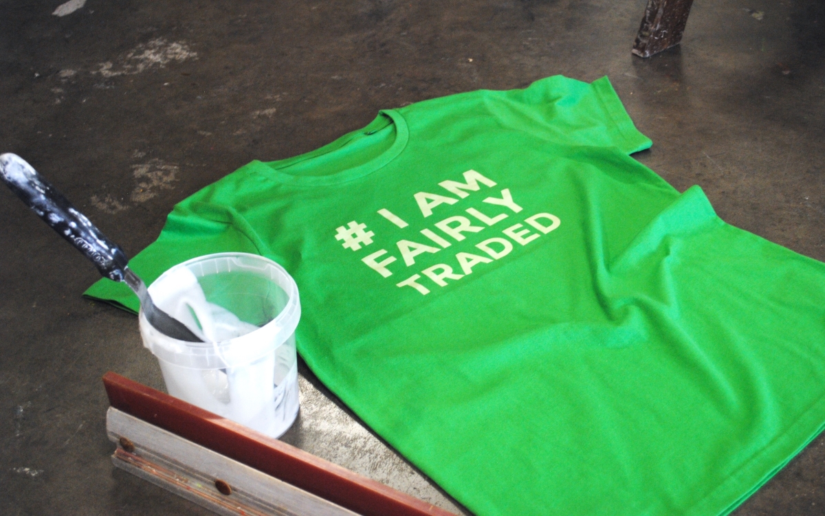 A green organic and fairtrade t-shirt on the ground with water-based ink with print on front , I am fairly traded