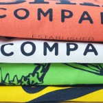 Four printed t-shirts stacked on top on each other in contrasting colours showing discharge print close up