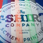 Close up of nine bella + canvas triblend t-shirts with a white discharge print on each